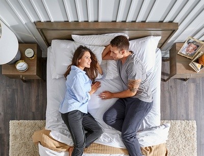 Man and woman laying in bed side by side looking at each other in bright room_square