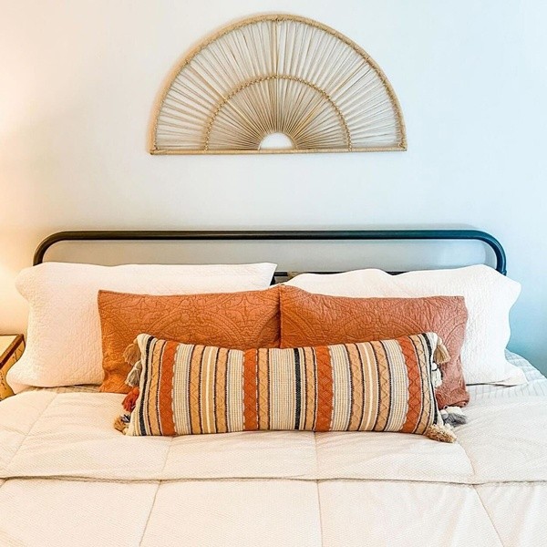 A dressed sealy mattress with orange throw pillows