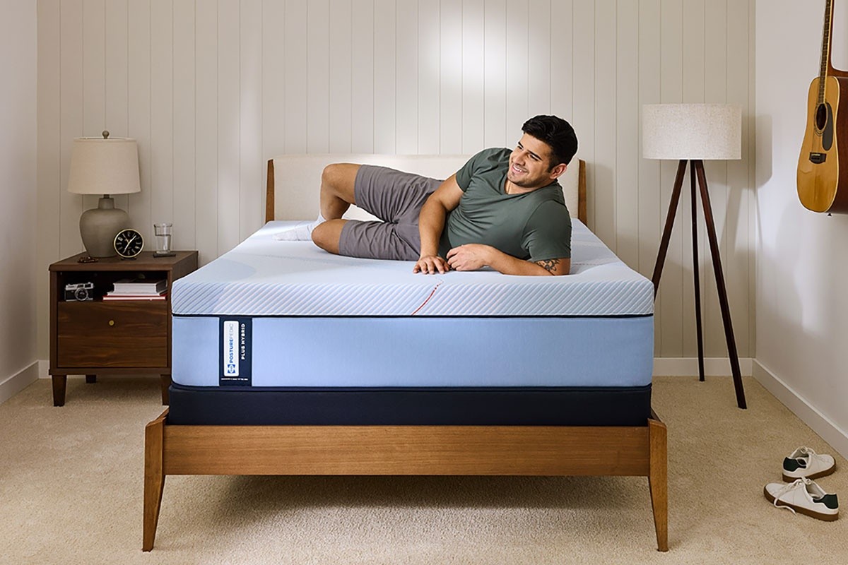 A man sitting on a Posturepedic Plus Hybrid in a styled room