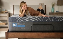 A woman laying on a Sealy Posturepedic Plus Hybrid Mattress