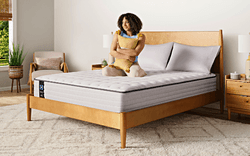 A woman model holding a pillow on a Posturepedic Spring mattress