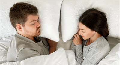 A couple laying on Sealy adjustable pillows