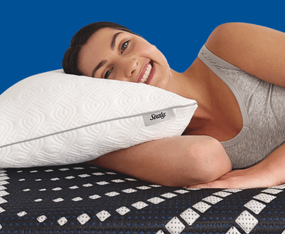 A woman laying on a Sealy adjustable pillow with blue background